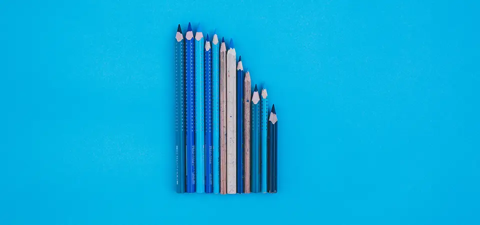 Pencils of different sizes over a blue background