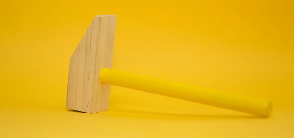 Wooden hammer painted in yellow in a yellow background